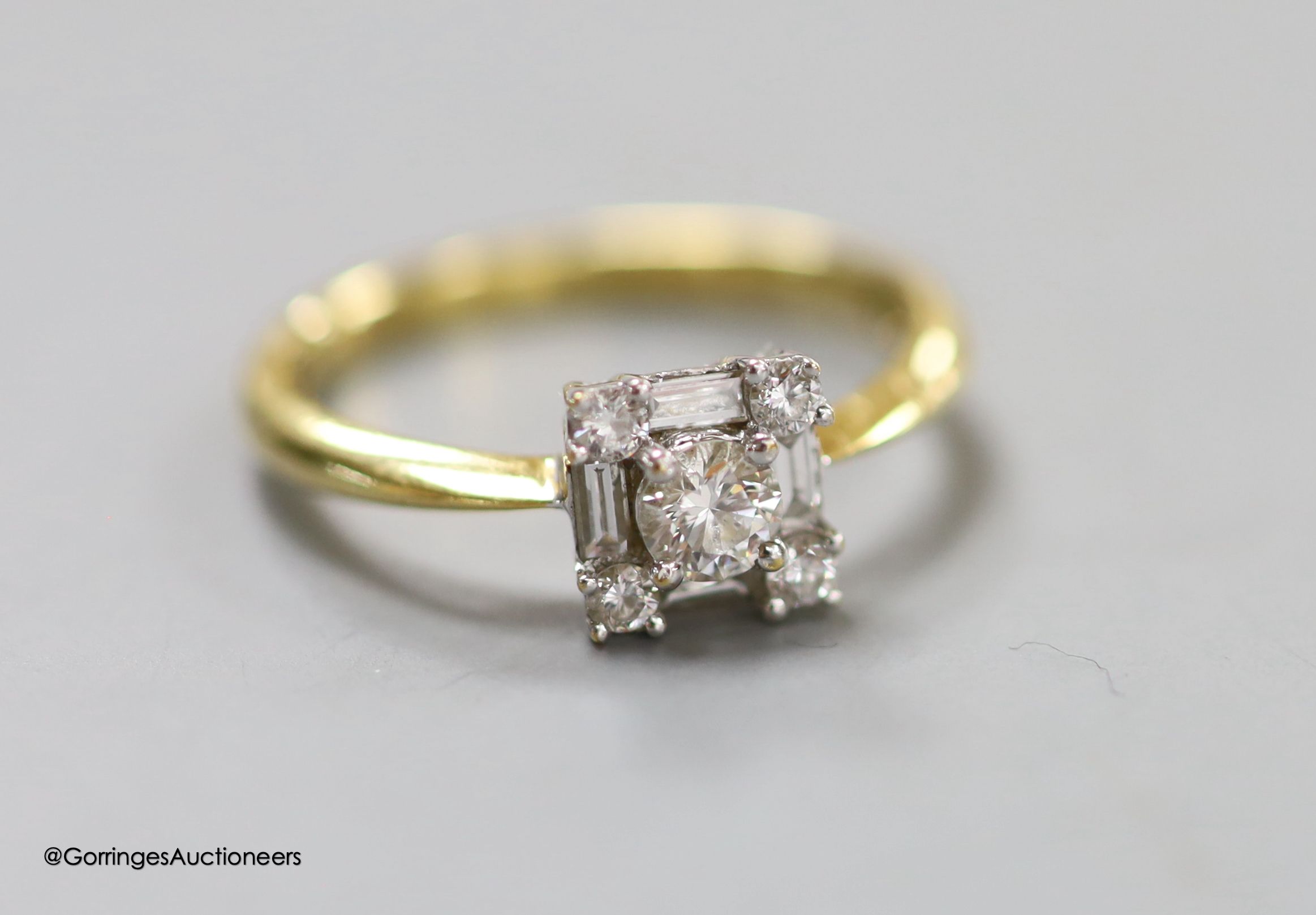 A modern 18ct gold, round and baguette cut diamond set square cluster ring, size N, gross 2.8 grams.